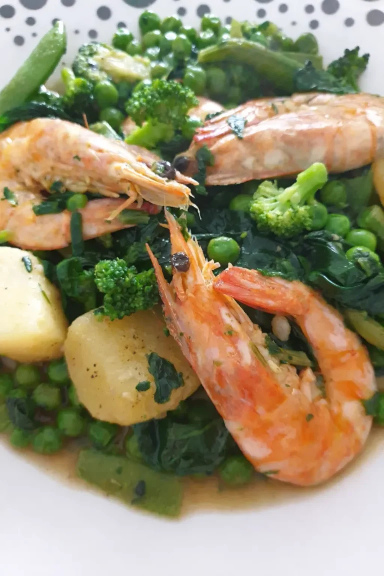 Assiette de légumes verts avec petits pois, pommes de terre et gambas, présentée en gros plan.