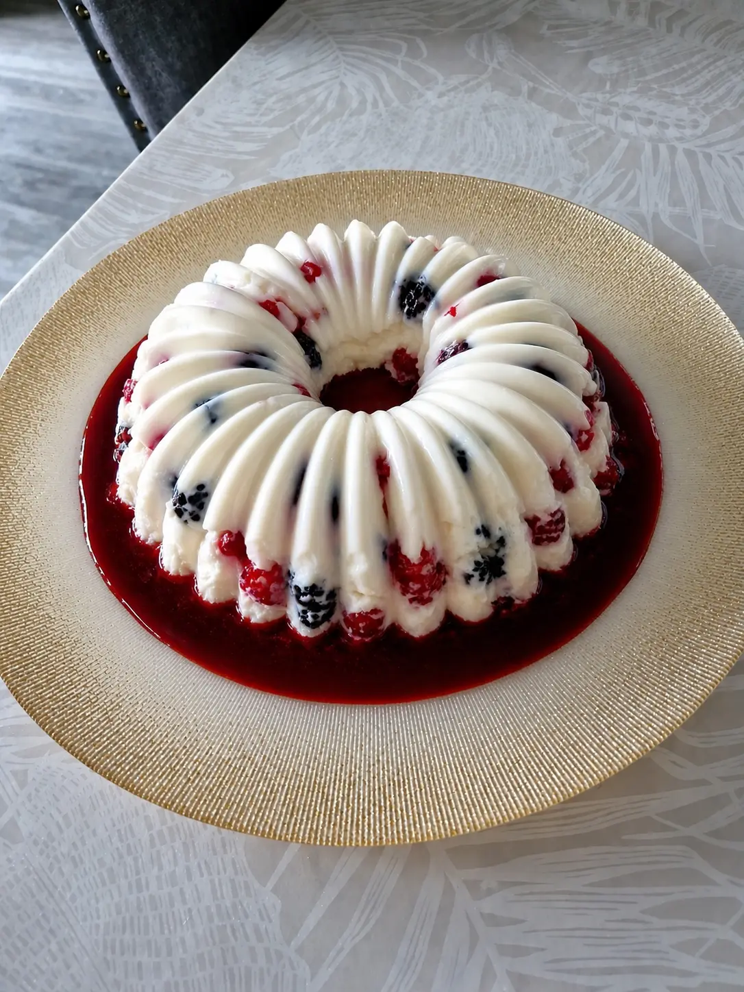 Délice frais aux fruits rouges en couronne, coulis rouge, texture fondante et fruits visibles